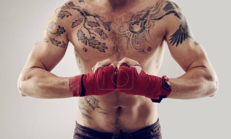 Téléchargez les photos : MMA, poing et enveloppements pour combattant masculin dans les arts martiaux, la boxe et en colère sur fond blanc. Mains, athlète et exercice pour homme kickboxer, studio et entraînement pour compétition de sport d'impact ou fitness. - en image libre de droit