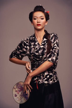 Foto de Mujer asiática, tradicional y de moda con espejo de mano en estudio sobre fondo marrón en confianza, estilo y elegante. Retrato, persona femenina y ropa de diseño con atuendo para la herencia - Imagen libre de derechos