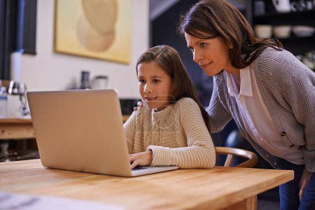 Photo for Mom, child and learning with laptop for support, care or browsing in the kitchen at home. Mother, daughter or kid typing on computer for social media, reading or helping girl on project or homework. - Royalty Free Image