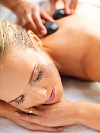 Photo for Woman, massage and relax in spa for hot stone, wellness and physical therapy for body, detox and luxury. Young person with eyes closed for rest and break for care, peace and treatment for holiday. - Royalty Free Image
