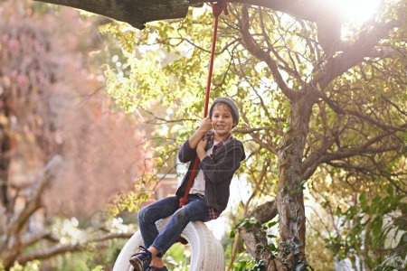 Photo for Boy, tyre swing and portrait in garden with happiness, playing and countryside vacation in summer. Child, face and diy adventure playground in backyard of home with sunlight, trees or smile in nature. - Royalty Free Image