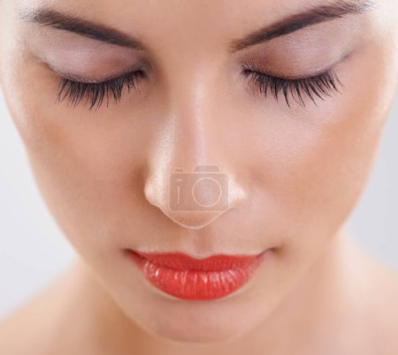 Woman, beauty and makeup in studio for cosmetics, dermatology and eyelash extension on a white background. Closeup, face and model or person with foundation, skincare and her eyes closed for results.
