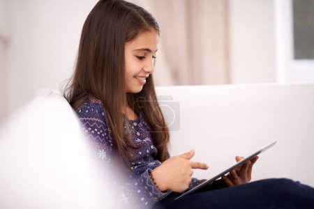 Photo for Relax, home or kid with tablet for streaming, playing games or watching fun videos on movie website. Social media, online or happy girl with technology to download on app or reading ebook on couch. - Royalty Free Image