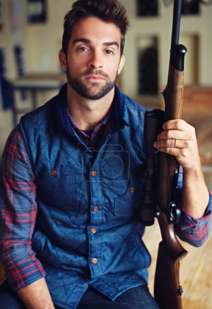 Photo for Hunter, confidence and portrait of man with gun for game shooting, adventure and hobby in home. Sports, trophy hunting and serious face of person in cabin with rifle, pride and sportswear in home. - Royalty Free Image