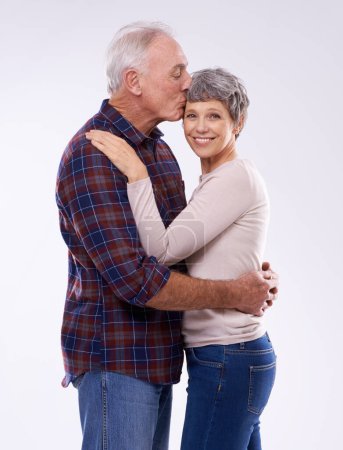 Photo for Portrait, kiss and senior couple on a white background for bonding, affection and happy relationship. Marriage, love and mature man and woman embrace for commitment, trust and care in studio together. - Royalty Free Image