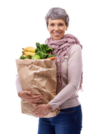 Téléchargez les photos : Femme, sac en papier et portrait avec des légumes pour le shopping, l'épicerie et le consommateur pour la nutrition et les fruits en studio. Dame mûre, heureux et tenir les produits pour la santé et la nourriture sur fond blanc. - en image libre de droit