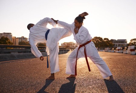 Photo for People, karate and fighting with personal trainer in city street for self defense, technique or style. Man and woman fighter or athlete in fitness training, martial arts or kick boxing in urban town. - Royalty Free Image