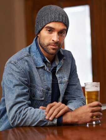 Photo for Portrait, beer and male person thinking at pub, drinks and restaurant for entertainment. Pensive, alcohol and bar for thoughtful or social for relax, smile and beanie for cold weather in England. - Royalty Free Image