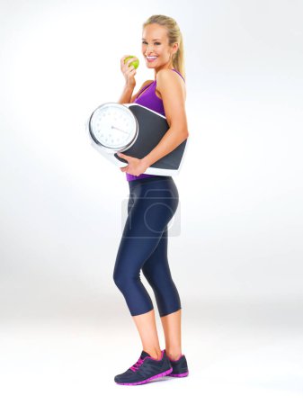 Photo for Woman, portrait and scale or apple for body, studio and excited for results of diet or detox. Female person, nutrition and journey for calories burned target, organic snack and white background. - Royalty Free Image