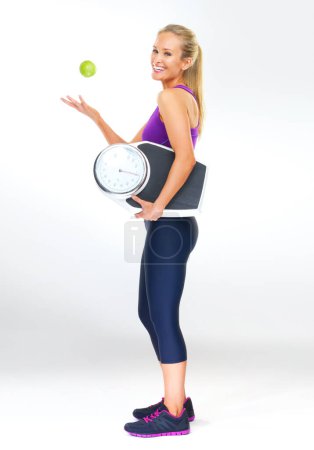 Photo for Woman, portrait and scale or apple for balance, studio and excited for results of diet or detox. Female person, nutrition and journey for calories burned target, organic snack and white background. - Royalty Free Image