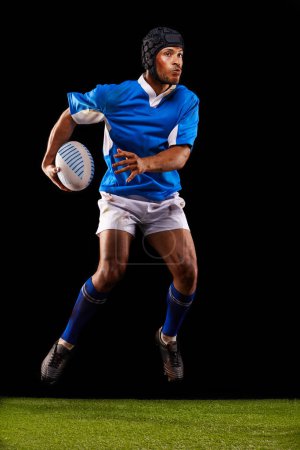 Photo for Jump, man and ball for rugby sport or training for workout, fitness and skill for competition. Person or player on grass and athlete practice or active for football game or match on black background - Royalty Free Image