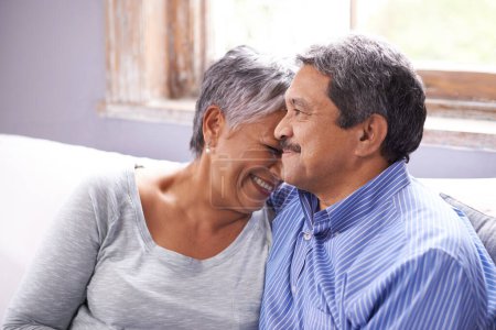 Téléchargez les photos : Couple heureux, amoureux et âgés sur le canapé avec rire pour une conversation drôle, coller et embrasser à la maison. Retraite, détente et personnes âgées avec le sourire pour plaisanterie, satisfaction et soutien dans le salon. - en image libre de droit