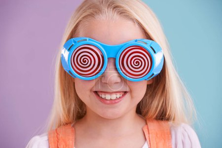 Photo for Child, studio and colour with fashion glasses, happy smile on girl with hypnotic cute eyewear. Groovy, funky and playful hipster style, trendy kid with cool vibrant bright pattern for accessories. - Royalty Free Image
