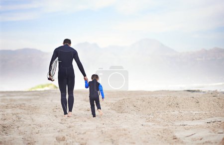 Photo for Surfboard, man and child on beach, walking and holding hands on outdoor bonding adventure. Nature, father and son at ocean for surfing, teaching and learning together with support, trust and growth - Royalty Free Image