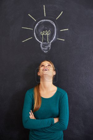 Photo for Idea, thinking and happy woman with light bulb on chalkboard for inspiration, brainstorming and problem solving. Creative, question and person on background for solution, thoughtful and planning. - Royalty Free Image