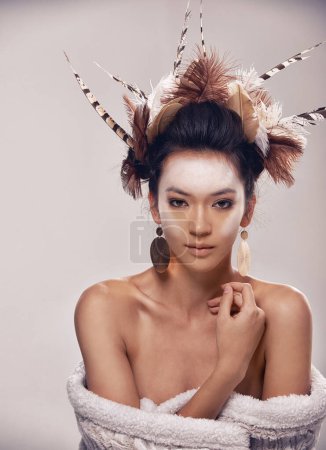Photo for Model, portrait and native american headdress in studio with feather, hair and beauty with culture cosmetics. Woman, face and indigenous make up or art and elegant fashion or cloth on grey background. - Royalty Free Image