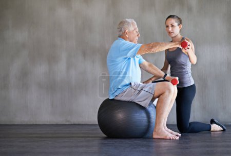 Photo for Physiotherapist, dumbbells and senior man on ball for fitness, rehabilitation or exercise at gym on mockup space. Elderly person, weightlifting or training for physical therapy, help or body health. - Royalty Free Image