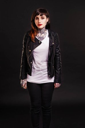 Téléchargez les photos : Portrait, tatouage et femme gothique dans une veste en cuir sur fond noir pour un style agressif en studio. Modèle punk féminin sombre, unique et cool avec de l'encre sur la peau pour l'art, la mode ou l'expression créative. - en image libre de droit