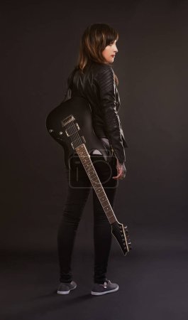 Photo for Woman, guitar and fashion for musical instrument, sound and trendy for retro and style on dark background. Young person, musician and artist for creative, funky and edgy for bold with leather jacket. - Royalty Free Image