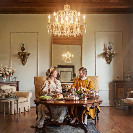Photo for Noble, couple and luxury with food, feast and renaissance home or house and dining table. King, queen and palace with royal dinner, rich meal and wealthy monarch or ruler with tudor era supper. - Royalty Free Image