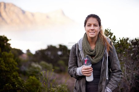 Photo for Woman, hiking and portrait in nature with bottle for water with fitness, hydration or smile on adventure. Girl, person and trekking in bush, mountains and rocks for journey on vacation in Cape Town. - Royalty Free Image