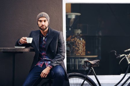 Photo for Portrait, city and man drinking coffee with bicycle at cafe table for breakfast in the morning. Bike, tea cup and serious person with espresso, latte or beverage at restaurant with winter fashion. - Royalty Free Image