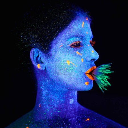 Photo for Neon, paint and creative woman in studio with plant for organic art, psychedelic aesthetic or cosmetics. Glow makeup, person or fluorescent glitter for uv illusion or fantasy glow on black background. - Royalty Free Image
