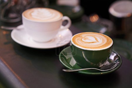Foto de Café en la mesa, taza con arte latte y creativa, capuchino o bebida de cafeína con patrón. Bebida caliente en mostrador, espuma y leche con diseño de corazón o hoja, hospitalidad y servicio en la cafetería. - Imagen libre de derechos