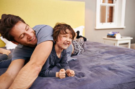 Photo for Happy, playing and father with child on bed bonding, relaxing and having fun together at modern home. Laughing, smile and young dad laying with boy kid in bedroom on weekend at family house in Canada. - Royalty Free Image