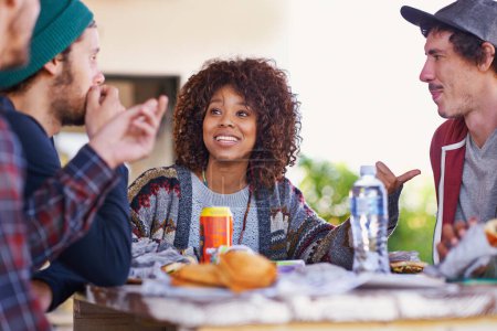 Photo for Friends, group and outdoor talking for eating lunch together on backyard patio for bonding, relaxing or connection. Men, women and smile with beverages for community gathering, communication or snack. - Royalty Free Image