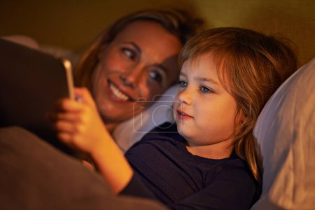 Photo for Night, mother or kid with tablet for streaming, playing games or watching videos on movie website in home. Social media, child or happy mom with smile or technology to download on ebook online in bed. - Royalty Free Image