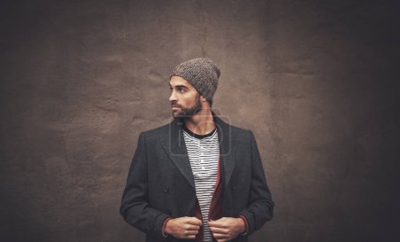 Photo for Man, serious and thinking with fashion in winter for trendy, warm clothes and cool style by brown wall. Male person, pride and pose with confidence for outfit, contemplating and thoughtful with idea. - Royalty Free Image