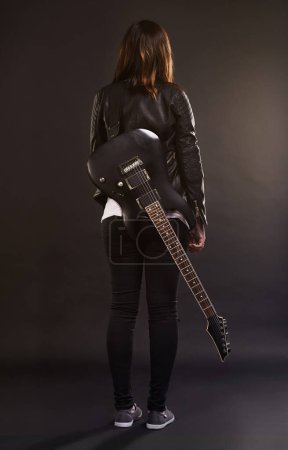 Photo for Woman, guitar and fashion for musical instrument, sound and trendy for retro and style on dark background. Young person or musician for creative, funky and edgy for bold with leather jacket for rock. - Royalty Free Image