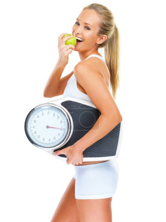 Photo for Scale, apple and woman in studio for weightloss for health, wellness and diet snack. Smile, fitness and portrait of female person eating fruit for exercise, workout or training by white background - Royalty Free Image