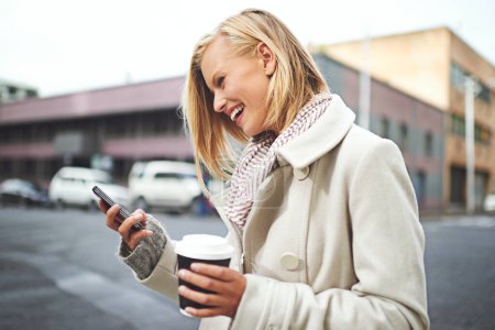 Photo for Woman, phone and and coffee in city, winter and texting for scarf, fashion or reading on metro road. Girl, person and happy with smartphone for typing on urban sidewalk by social media in Cape Town. - Royalty Free Image