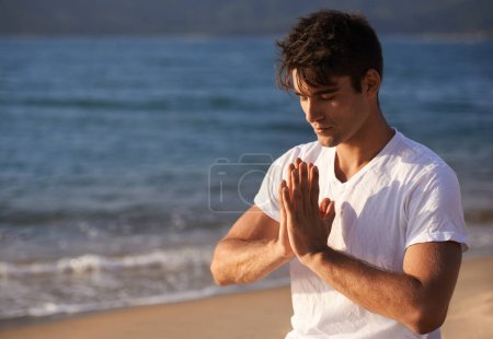 Foto de Meditación, manos con oración y hombre en la playa, mindfulness y zen con aire fresco para la calma al aire libre. Océano, costa y viajes con yoga para la salud, la paz de la mente y la curación holística para el aura. - Imagen libre de derechos
