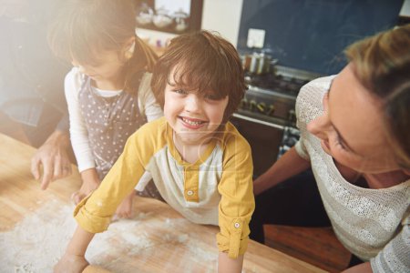 Photo for Portrait, kid and happy family baking food in kitchen together, preparation and learning in home. Face, mother and father with children cooking, teaching and help parents with flour dough at table. - Royalty Free Image