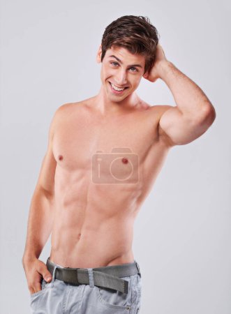 Photo for Happy, portrait and handsome man with muscular body in fitness, health or wellness on a gray studio background. Attractive, young male person or model with smile and abs in confidence or satisfaction. - Royalty Free Image