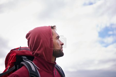 Photo for Sky, hiking and man with backpack, thinking and outdoor in nature for adventure, peace and travel. Contemplation, mindfulness and male person looking up, thoughtful and journey for holiday and break. - Royalty Free Image