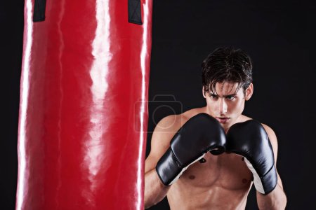 Téléchargez les photos : Fitness, boxe ou homme avec sac de boxe en studio pour l'entraînement d'exercice, de défi ou de compétition. boxeur de puissance, de muscle ou de champion à l'entraînement avec confiance, combat d'arts martiaux et fond noir. - en image libre de droit