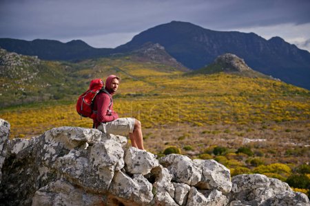 Photo for Man, rocks and relax on outdoor hike in nature, solitude and peace or calm on rocks for wellness. Male person, exercise and travel with backpack on vacation, adventure and explore bush for fitness. - Royalty Free Image