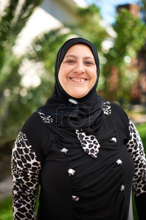 Foto de Mujer madura, musulmana y feliz en el jardín para eid o ramadán para la religión para disfrutar y satisfecho. Fe, Islam y sonrisa como persona femenina por la esperanza con atuendo para mezquita y oración en retrato. - Imagen libre de derechos