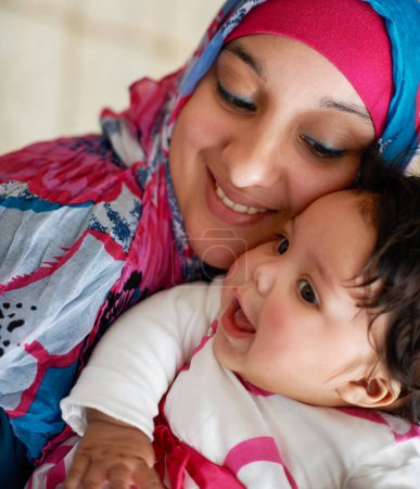 Téléchargez les photos : Heureux, musulman et maman avec bébé à la maison avec amour et soins pour la famille en Arabie Saoudite. Bébé, enfant et mère arabe se détendre dans la maison avec le soutien et la gentillesse pour les enfants dans l'étreinte ou câlin avec maman. - en image libre de droit