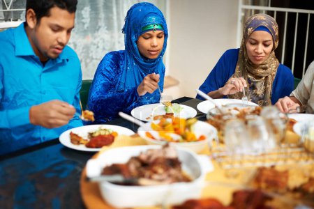 Téléchargez les photos : Famille, manger et la maison avec de la nourriture pour l'aigle, l'islam et la célébration autour de la table et heureux avec la cuisine. Peuple islamique, hommes et femmes et ensemble pour le ramadan dans la maison pour la conversation et le déjeuner. - en image libre de droit