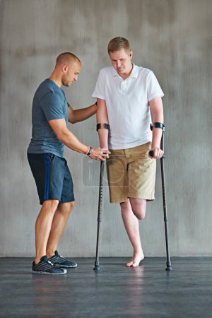 Photo for Man, amputee and crutches in physical therapy with personal trainer for rehabilitation and recovery. Male person with disability, exercise and fitness growth for health, vitality and strength. - Royalty Free Image
