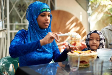 Foto de Familia, musulmán y mesa con postre para ramadán o eid para fiesta religiosa, celebración y comer en casa. Islam, tradicional y gente con hiyab para el festival, la cultura y la comida para ayunar. - Imagen libre de derechos