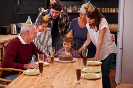 Photo for Family, birthday cake and happy kid with mom, dad and grandparents together with people and candles. Youth, smile and dessert with children and celebration with event food and party hats at a table. - Royalty Free Image