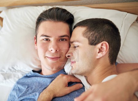 Photo for Portrait, men and top view of gay couple in bed at home to relax, embrace and bonding together in the morning. Lgbtq, face and people in bedroom for love, connection and healthy relationship in house. - Royalty Free Image