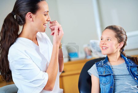 Photo for Professional, dentist and child with floss, girl or smile in a modern office or wellness with care. Trust, support or oral hygiene with string or patient with dental healthcare or cheerful with child. - Royalty Free Image