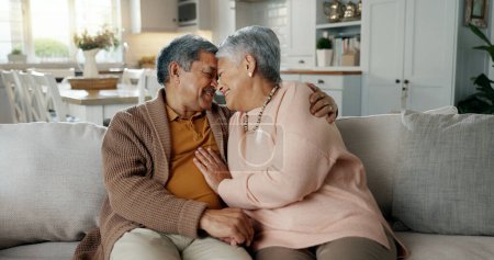 Téléchargez les photos : Couple sénior, visage et câlin sur canapé, sourire et se lier d'amour, de soutien et de détente à la retraite à la maison. Femme âgée, vieil homme et heureux avec étreinte, ensemble et assis sur le canapé du salon. - en image libre de droit